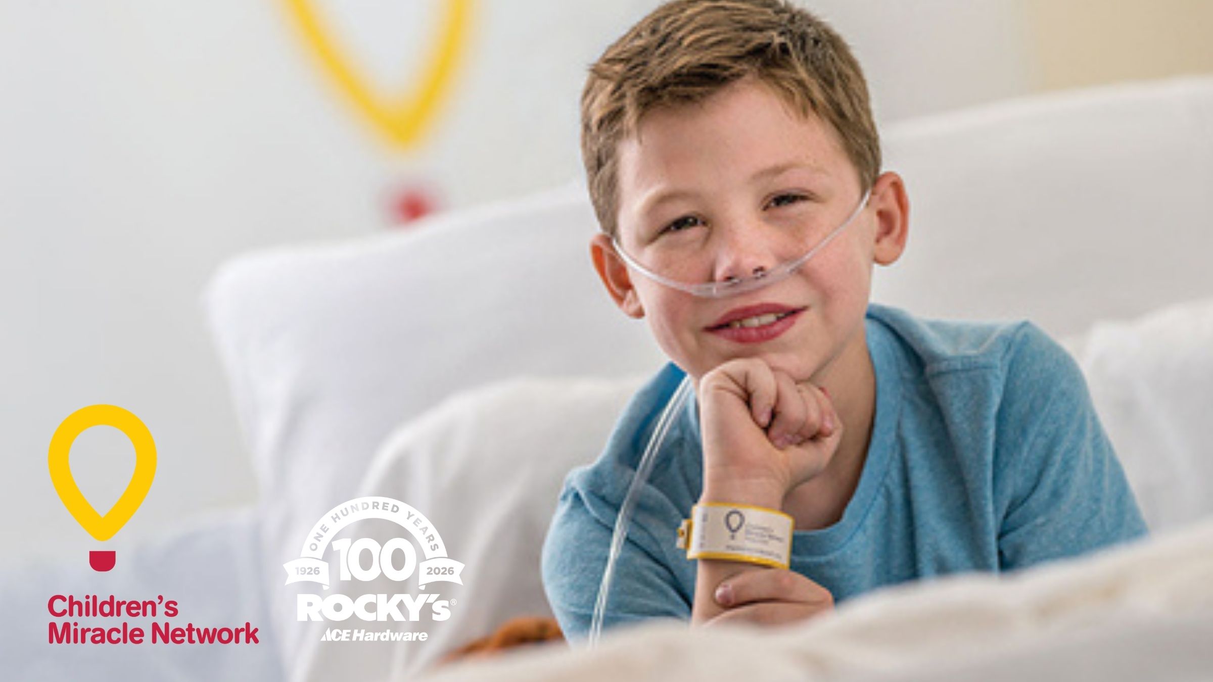 A child in a hospital bed, smiling, the Children's Miracle Network Logo visible in the background.